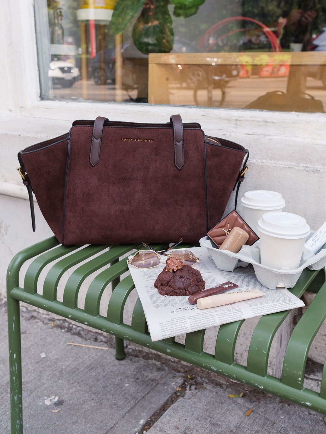 Poppy & Peonies Avenue Tote in Espresso Suede styled on a park bench with coffee and everyday essentials, showcasing its spacious silhouette, soft suede exterior and long top handles.