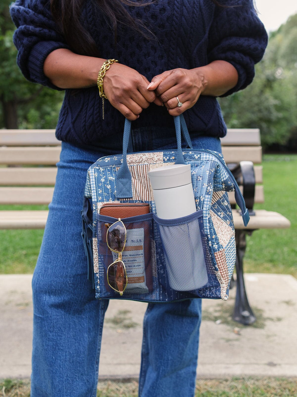 Close-up lifestyle shot of the Poppy & Peonies The Lunch Bag in Navy Patchwork with the front pocket packed with everyday essentials, highlighting its convenient exterior storage.