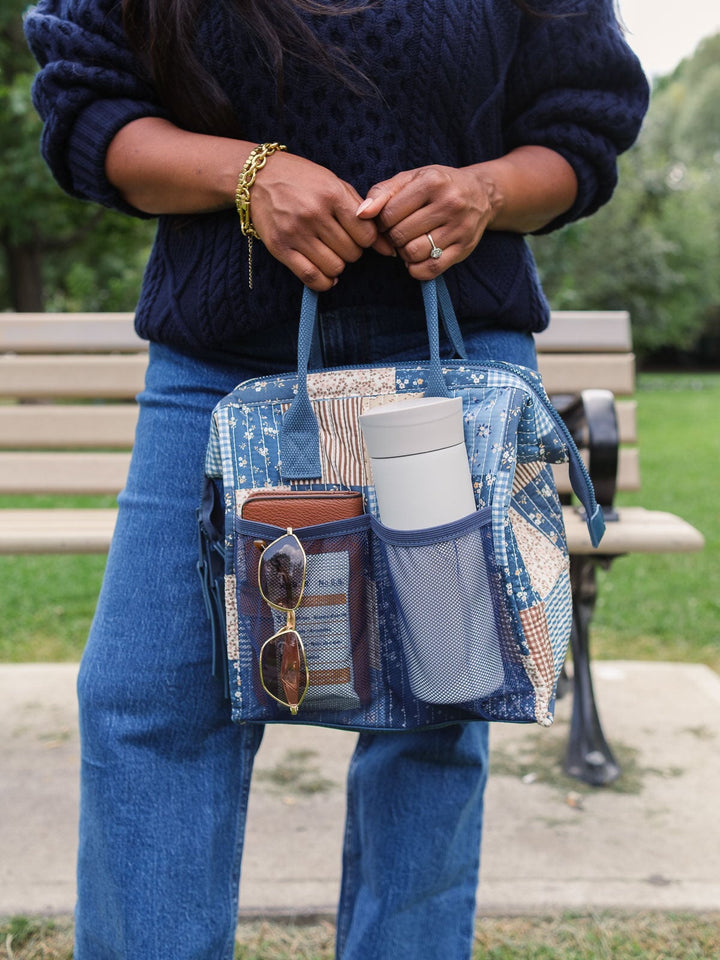 Close-up lifestyle shot of the Poppy & Peonies The Lunch Bag in Navy Patchwork with the front pocket packed with everyday essentials, highlighting its convenient exterior storage.