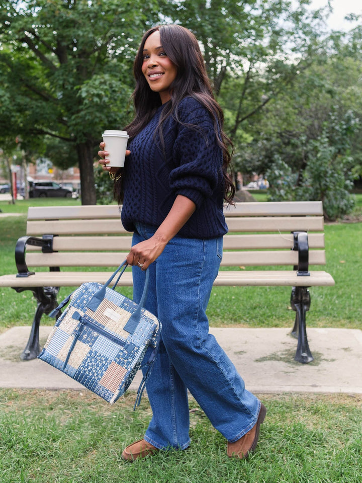 Lifestyle shot of a woman walking with the Poppy & Peonies The Lunch Bag in Navy Patchwork carried by its top handles, highlighting its portable everyday design.