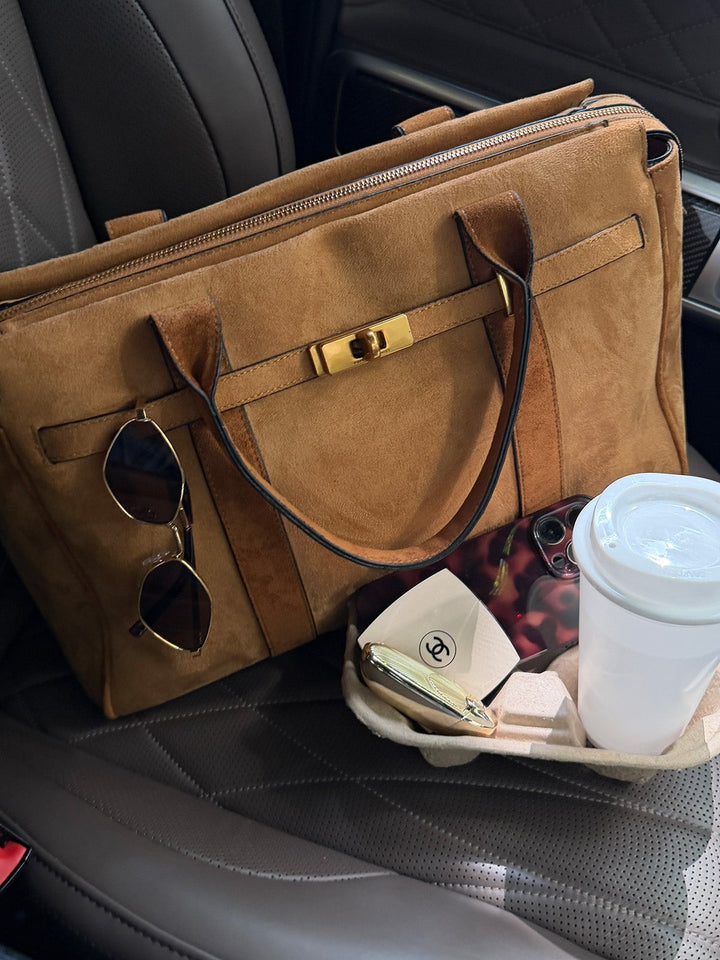 Poppy & Peonies Effortless Tote in Cognac Suede displayed on a vehicle seat with sunglasses, a phone, wallet and takeaway coffee, showcasing its travel-ready everyday size.