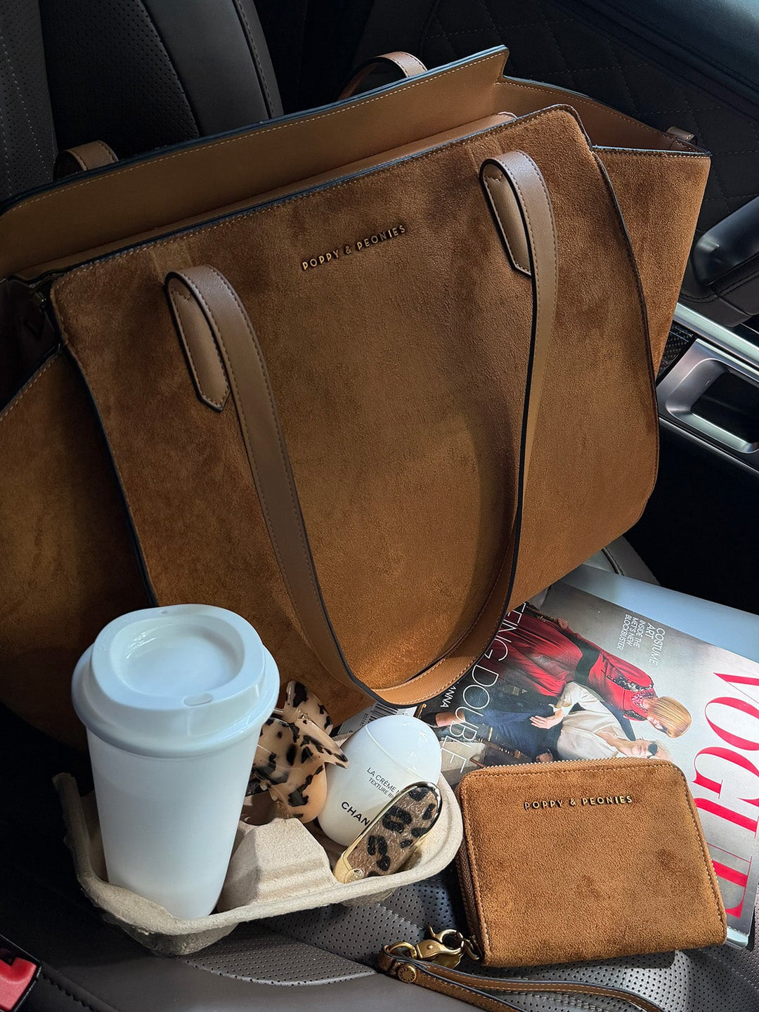 Poppy & Peonies Avenue Tote in Cognac Suede displayed on a car seat with a coffee and everyday essentials, highlighting its spacious size and smooth vegan leather straps.