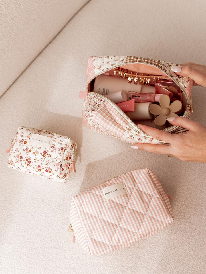 Pink floral and striped makeup bags on a light surface