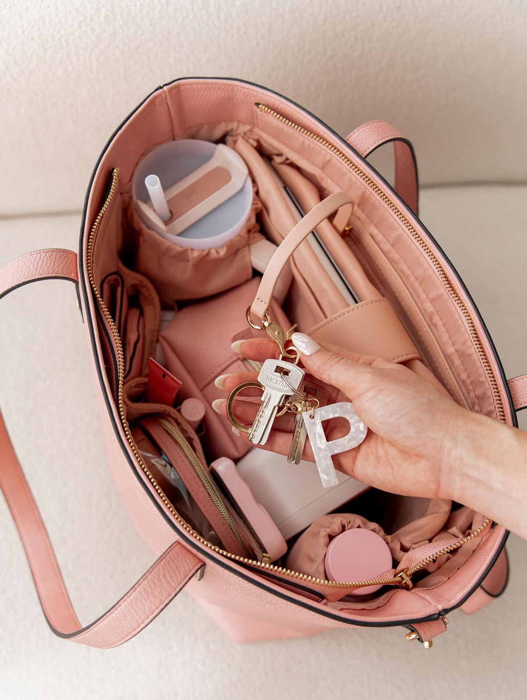 Pink handbag with keys and a letter 'P' charm, on a light background