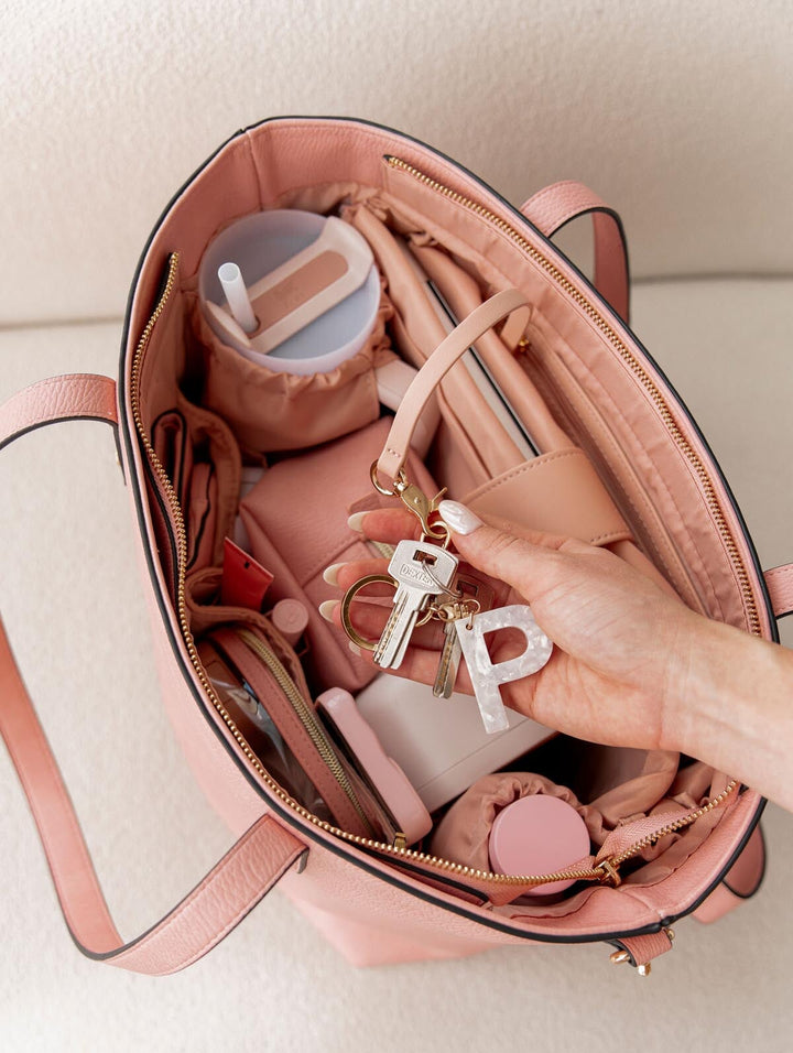 Pink handbag with keys and a letter 'P' charm, on a light background