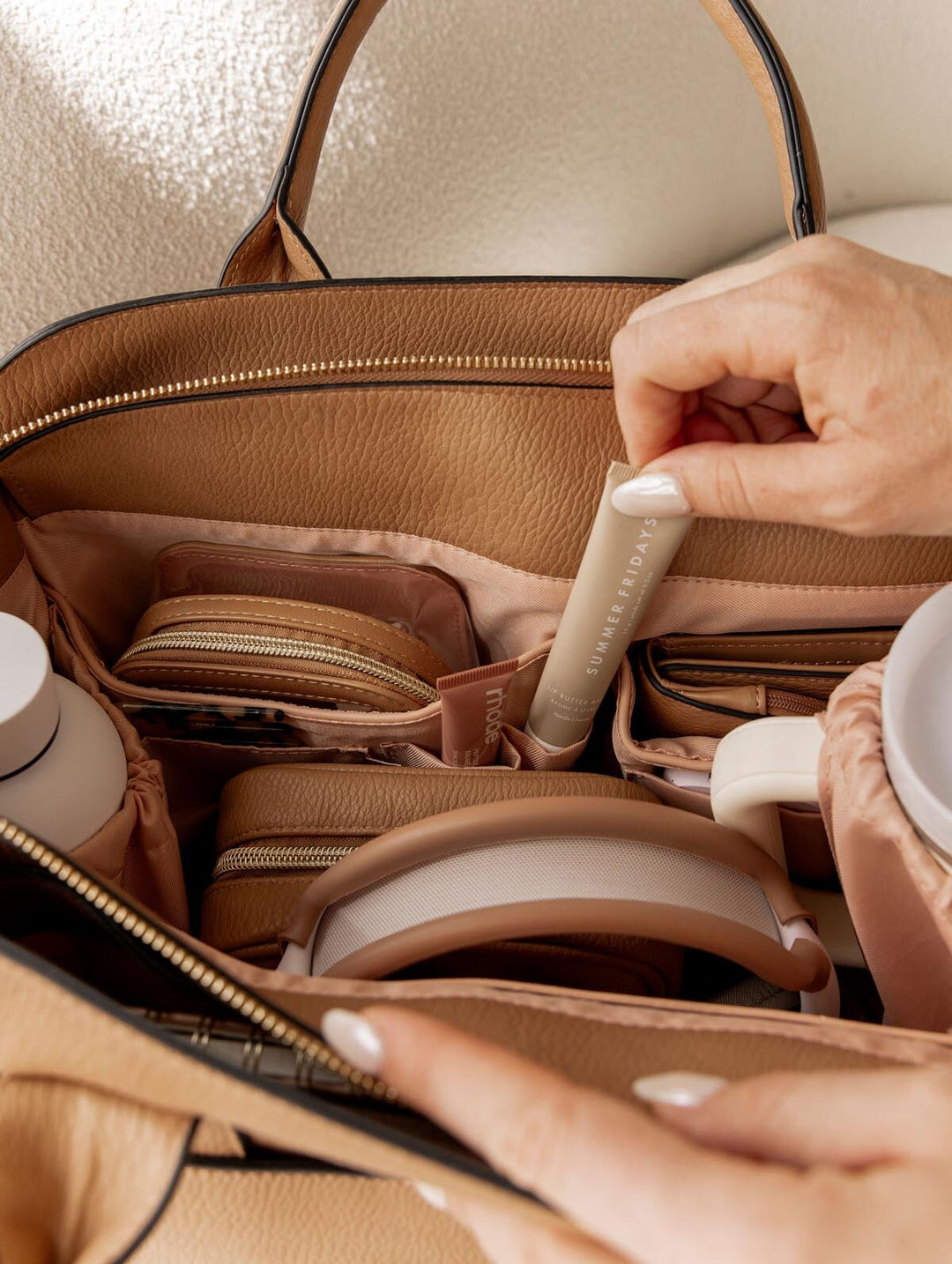 Hand pulling a lip balm out of a tote bag