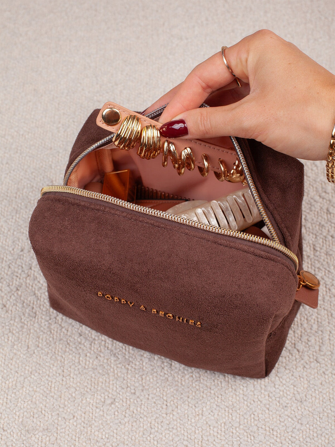 Open view of Poppy & Peonies Cosmetic Case in Espresso Suede, showing the organized interior with makeup brushes, beauty products and a jewelry holder.