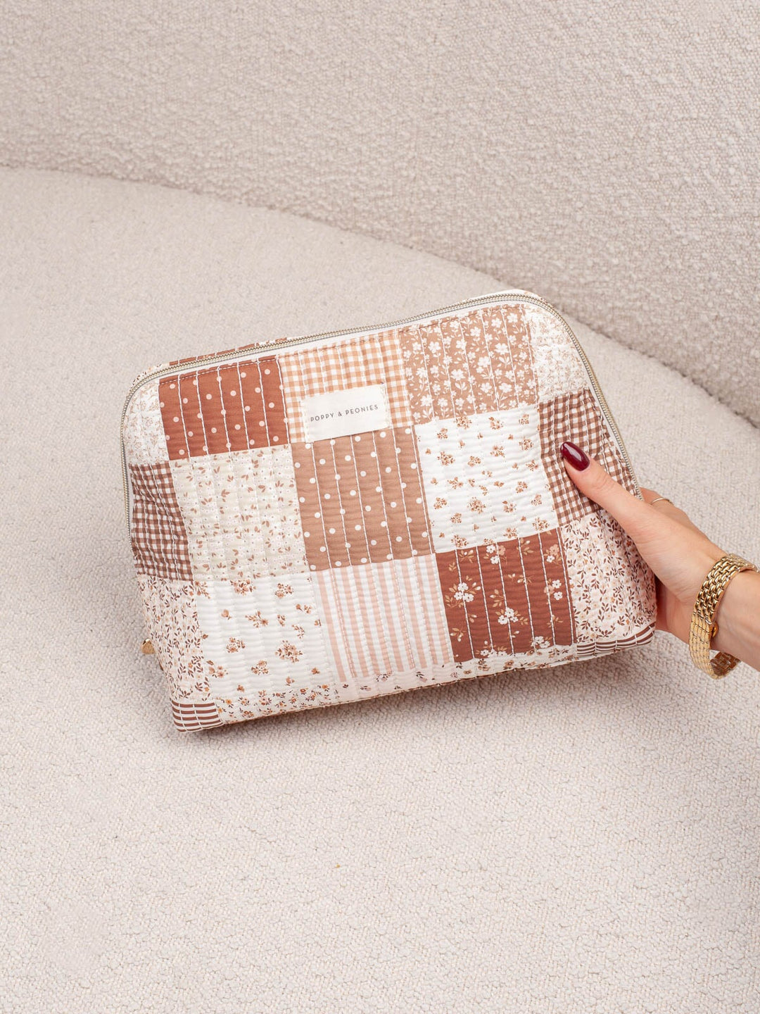 Poppy & Peonies Sitting Pretty Cosmetic Case in Brown Patchwork held by hand.