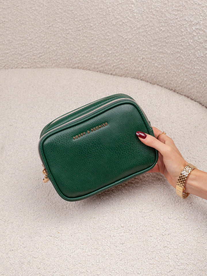 Handheld lifestyle shot of the Pretty Connected Case in Heritage Green, showcasing its rich green exterior, structured silhouette, and gold-tone branding. 