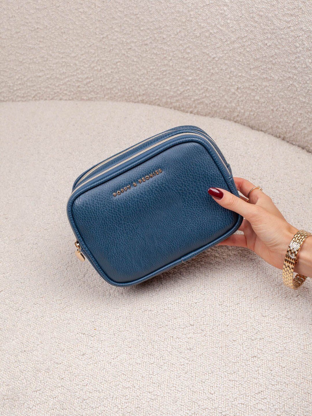 Product-focused lifestyle shot of The Split Organizer in Navy, highlighting its compact rectangular shape, rich navy finish, and zip-around closure.