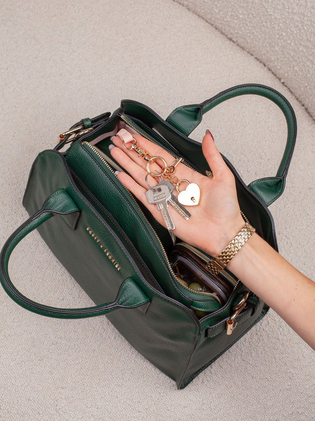 Lifestyle shot of the Mini Uptown Tote in Heritage Green, highlighting its organized interior and convenient key leash with keys attached.