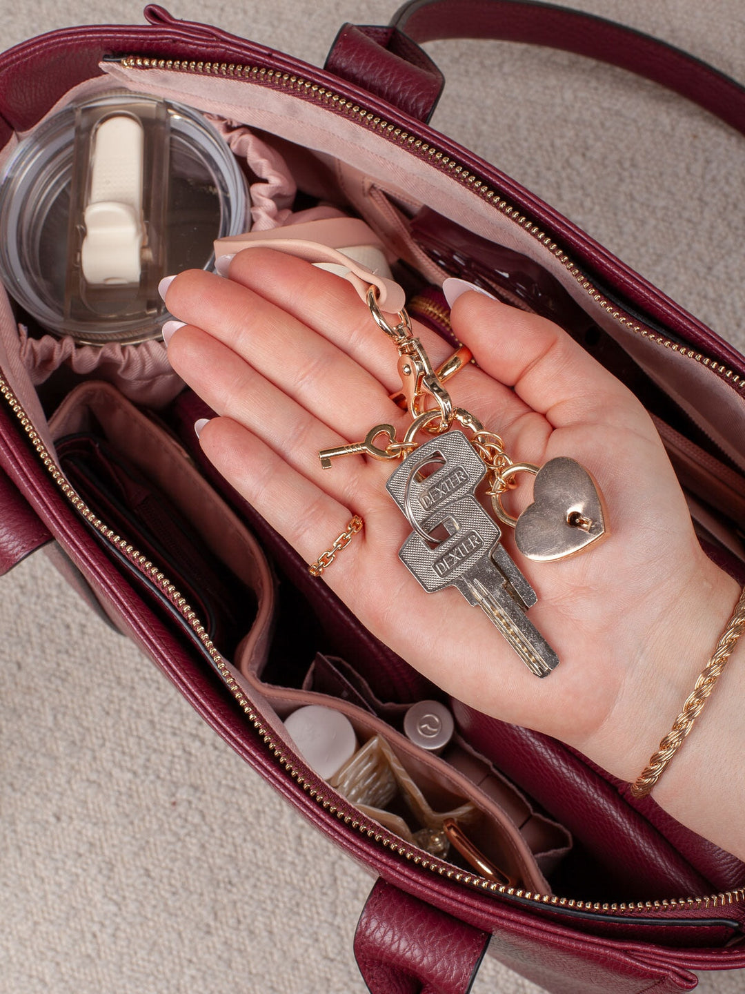 Detail lifestyle shot of the Small Multitasker in Berry, highlighting the organized interior and convenient key leash with keys attached.