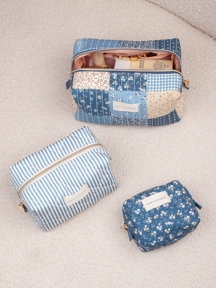 Lifestyle shot of the Cosmetic Trio in Navy Patchwork, showcasing all three coordinating cosmetic cases in blue floral, striped, and patchwork prints.