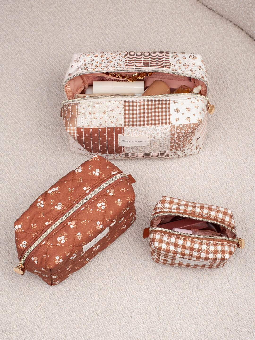Lifestyle shot of the Cosmetic Trio in Brown Patchwork, showcasing all three coordinating cosmetic cases in brown floral, gingham, and patchwork prints.
