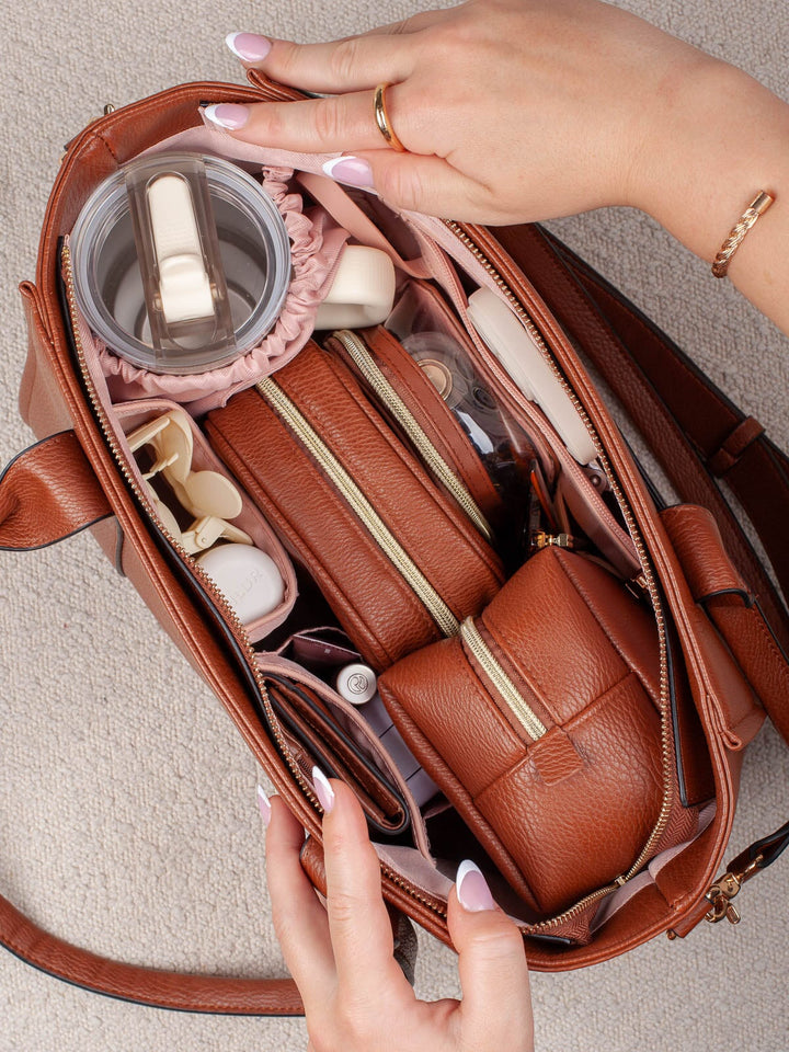 Overhead lifestyle shot of the Small Multitasker in Chestnut, showcasing its structured interior with coordinating pouches and dedicated storage for everyday essentials.