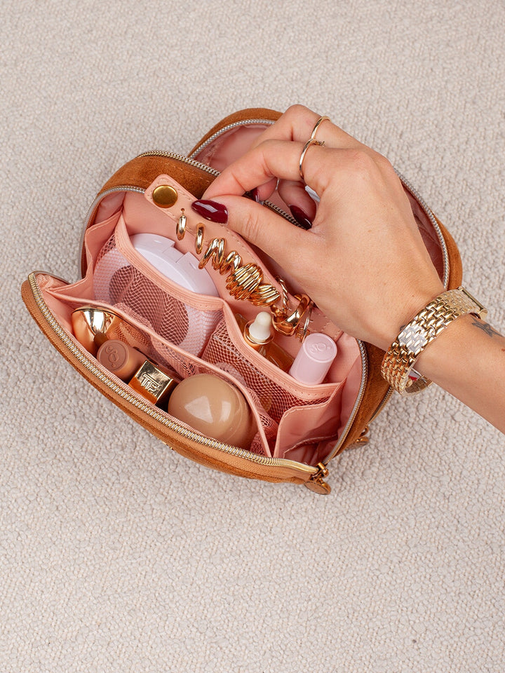 Close-up of Poppy & Peonies Pretty Connected Case in Cognac Suede, showing the blush-pink interior compartments filled with small accessories and everyday essentials.