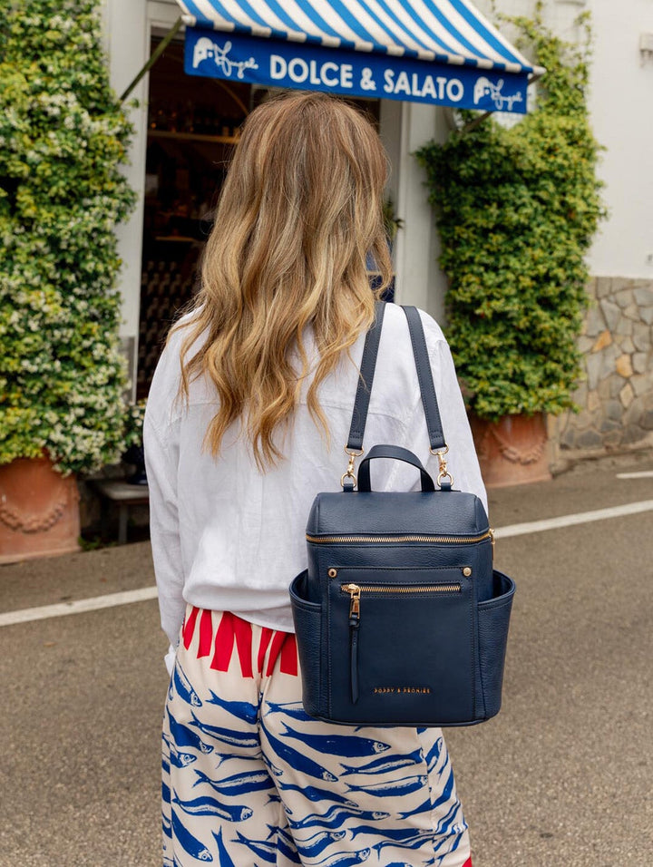 Woman wearing a blue backpack, standing in front of a Dolce & Salato store.