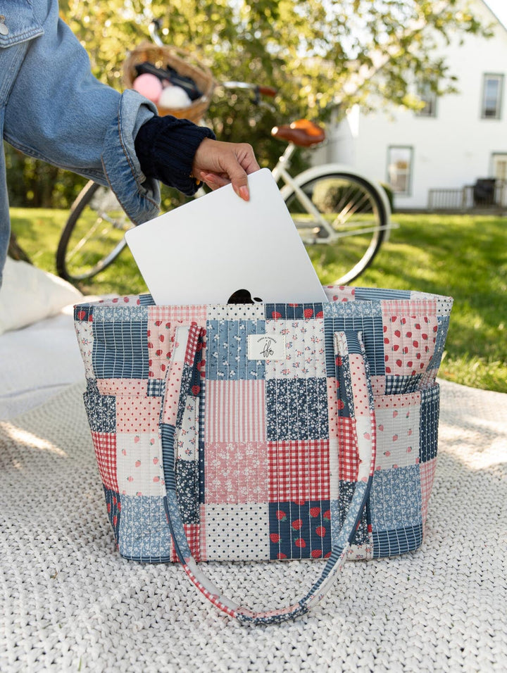 Poppy & Peonies Analog Tote in Strawberry Patchwork close-up, featuring a laptop being placed inside the spacious tote.