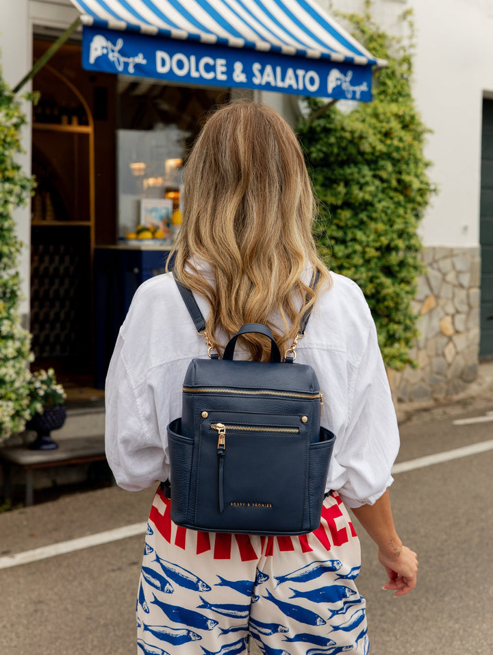 Person wearing a blue backpack in front of a Dolce & Salato store.