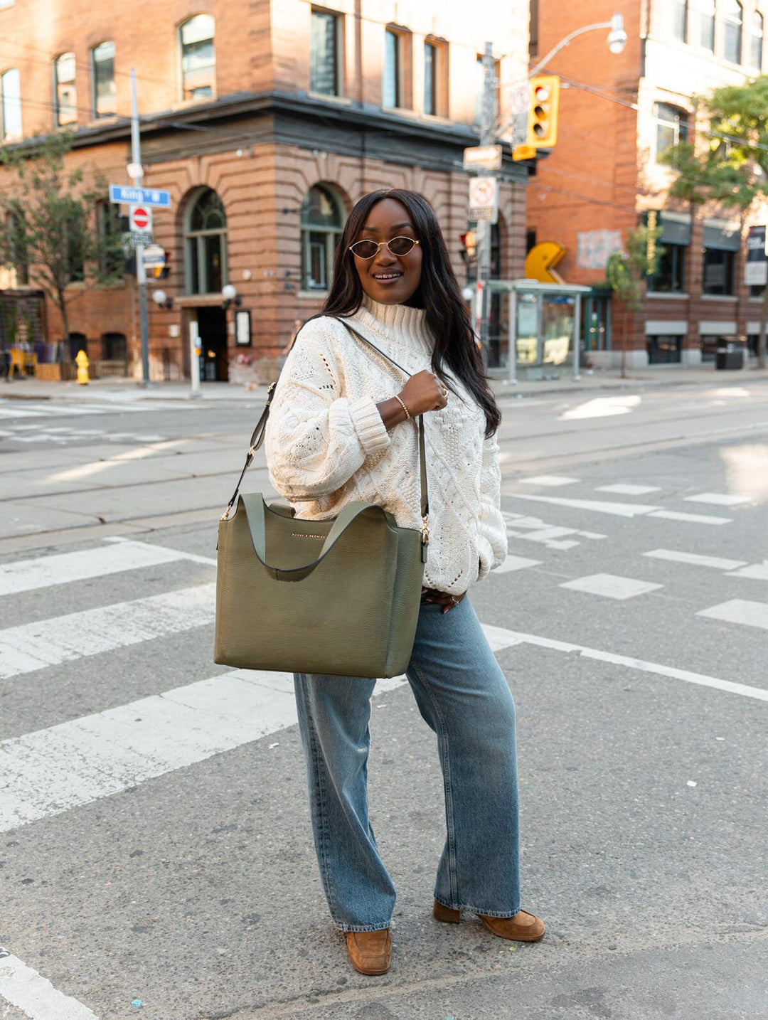 The Companion Tote in Olive styled over the shoulder in an outdoor lifestyle view, showcasing its everyday size and structured silhouette.