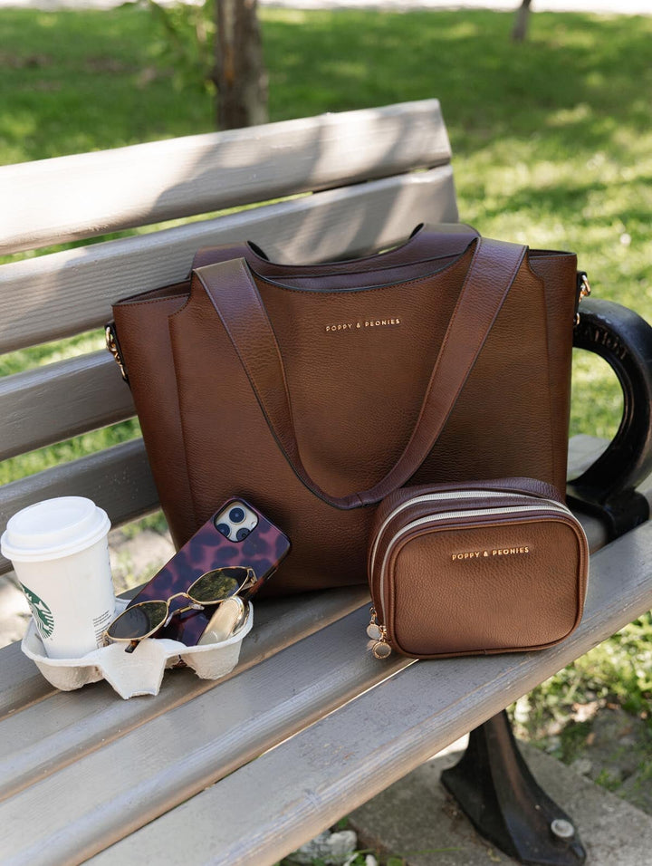 Poppy & Peonies Companion Duo in Espresso displayed on a park bench, featuring The Companion Tote and coordinating Pretty Connected Case.