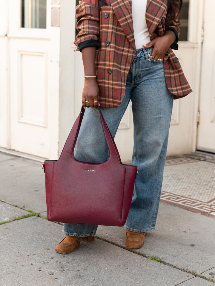 Poppy & Peonies The Companion Tote in Berry close-up lifestyle view, carried by the top handles with a plaid blazer and jeans.