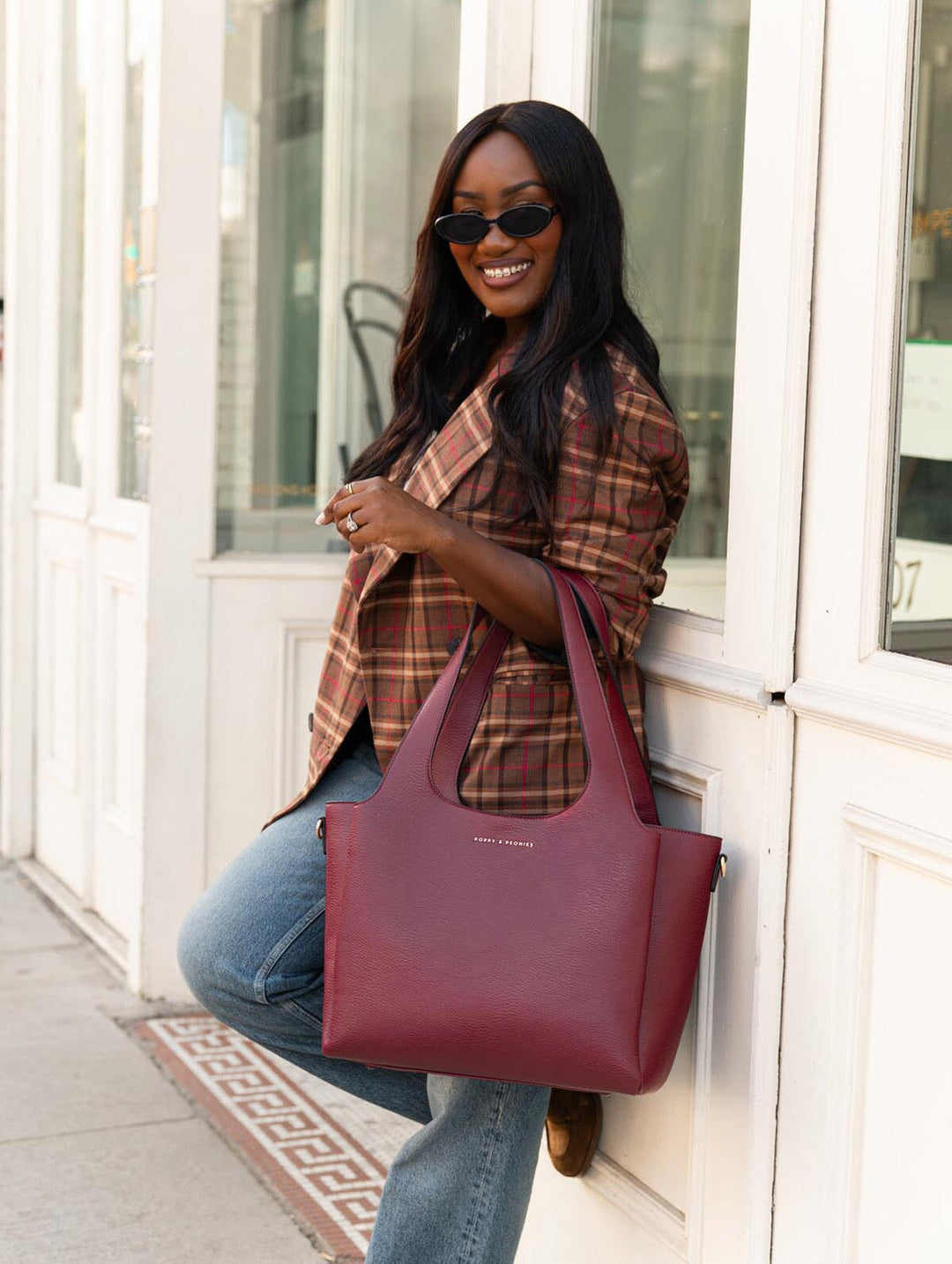 Poppy & Peonies The Companion Tote in Berry close-up lifestyle view, carried by the top handles with a plaid blazer and jeans.
