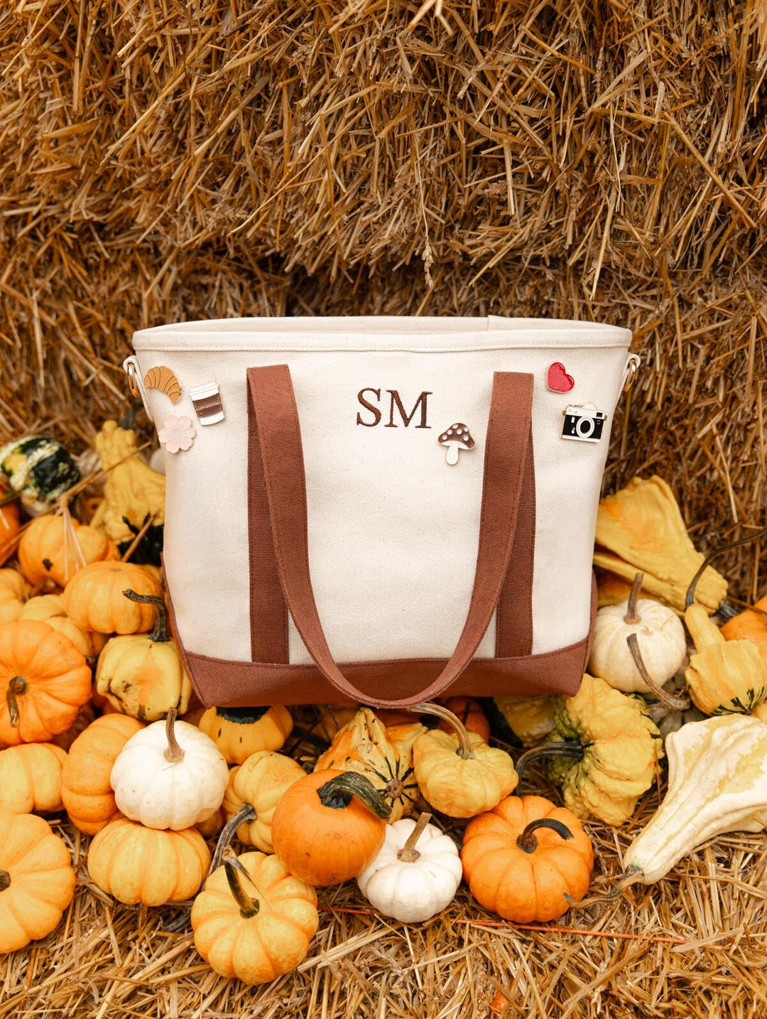 Poppy & Peonies The Small Signature Tote in Chestnut with personalized initials, displayed on a hay bale surrounded by autumn pumpkins and gourds.