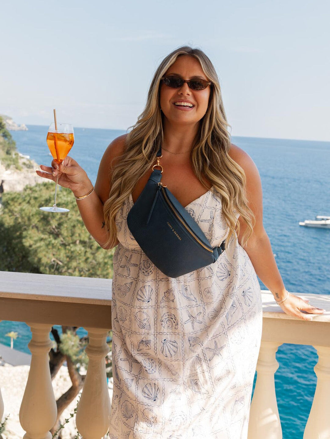 Woman wearing a white dress and navy blue crossbody bag