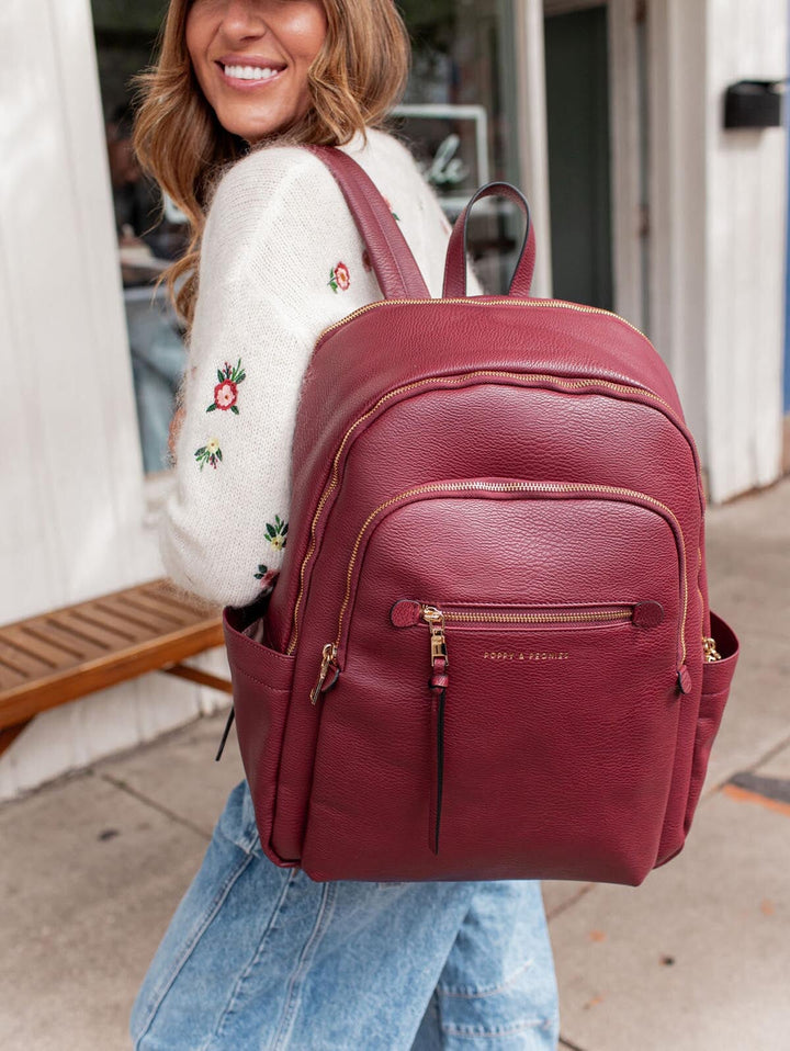 Woman carrying a berry coloured vegan leather backpack outdoors