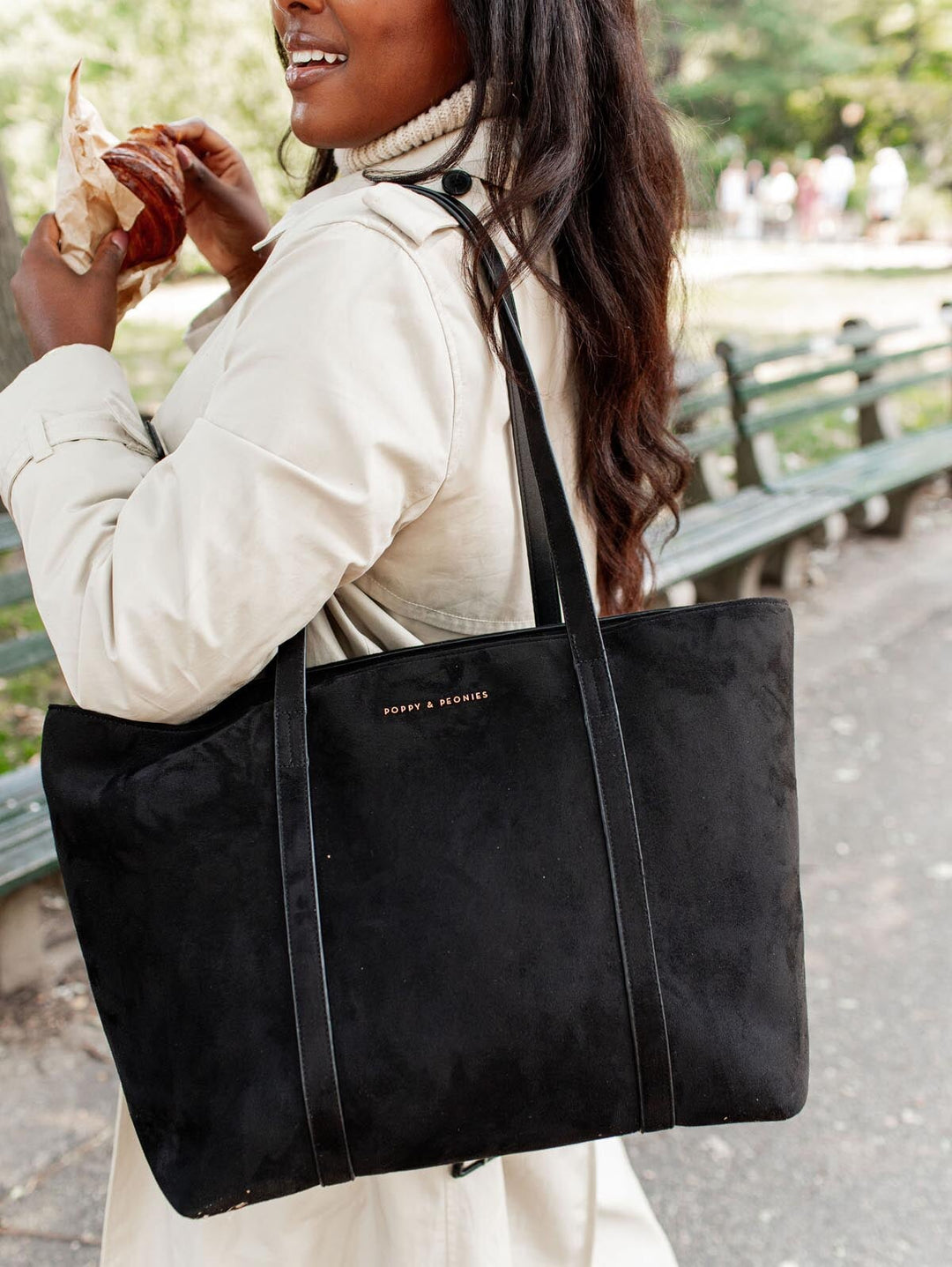 Woman carrying a black vegan suede tote bag in an outdoor setting