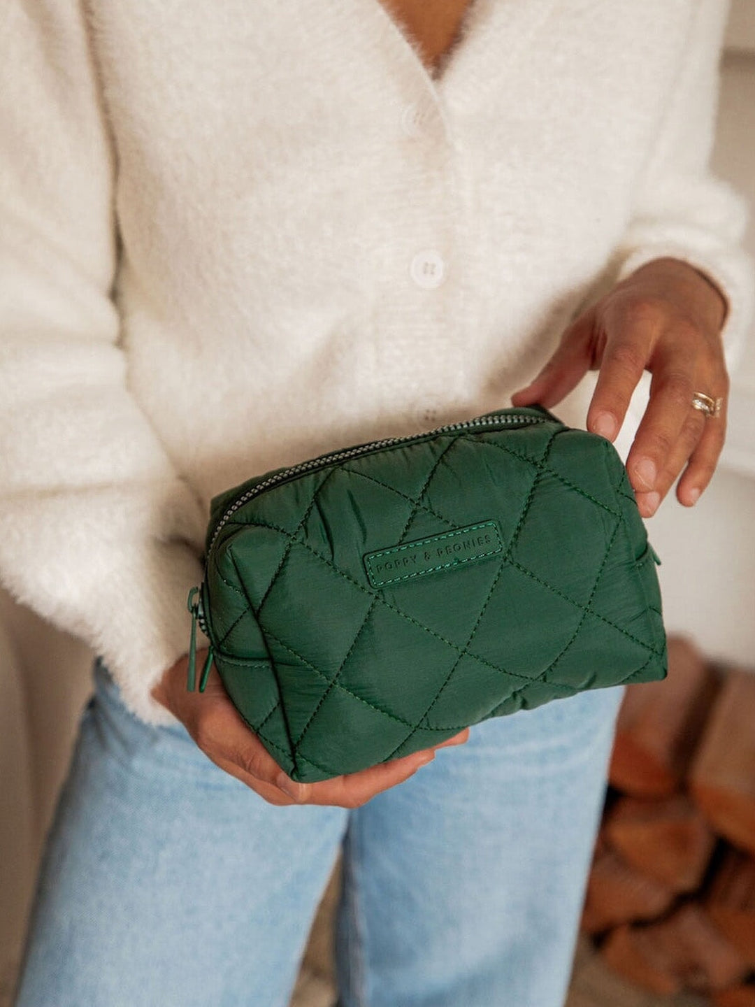 Person holding a green quilted makeup bag