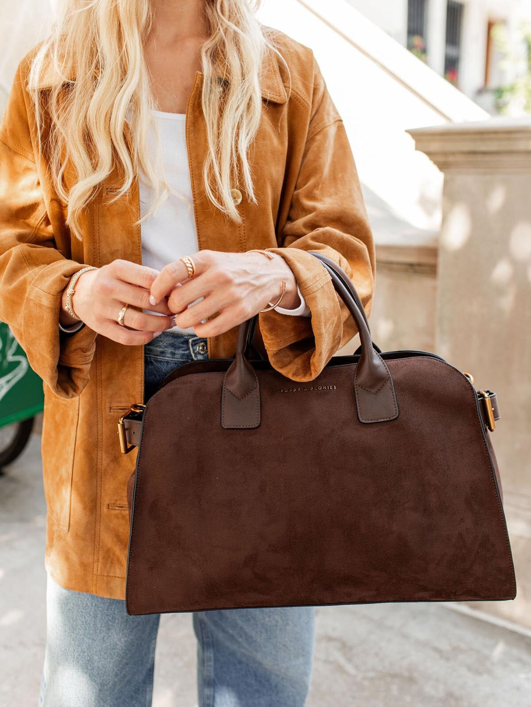 Person holding a brown vegan suede bag outdoors