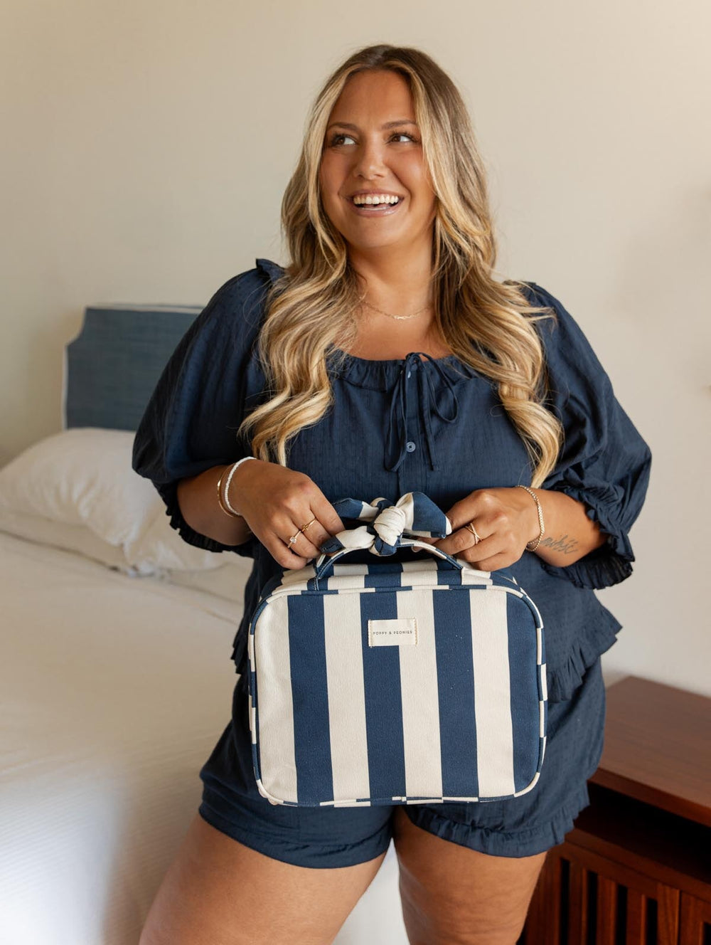 Woman holding a navy and white striped hanging cosmetic case