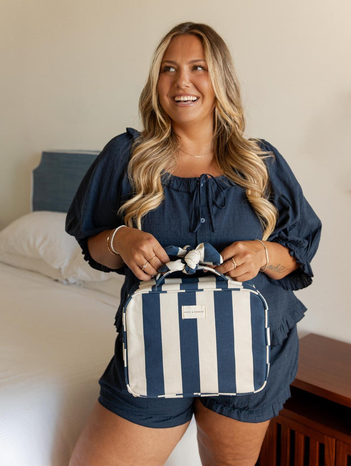 Woman holding a navy and white striped hanging cosmetic case