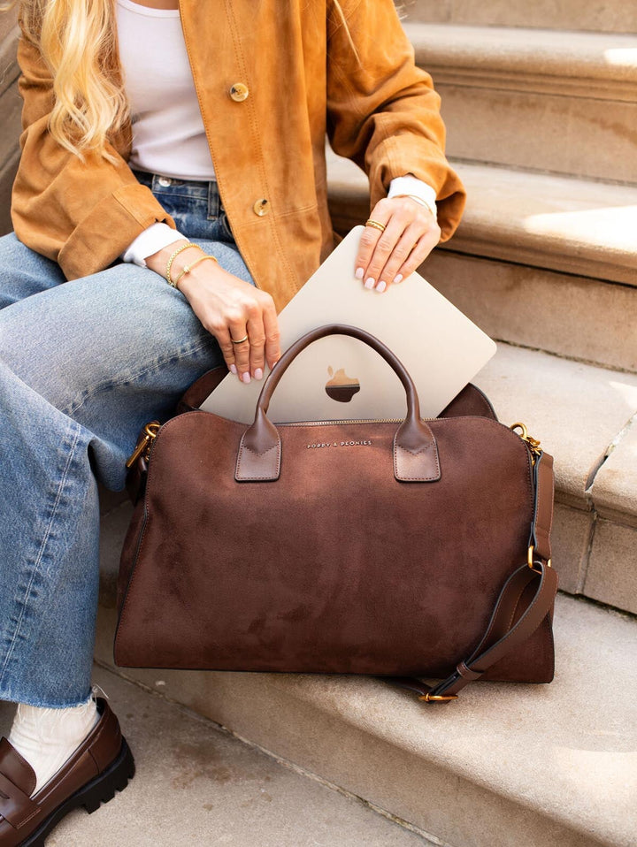 Person taking a laptop out of a brown vegan suede handbag on steps
