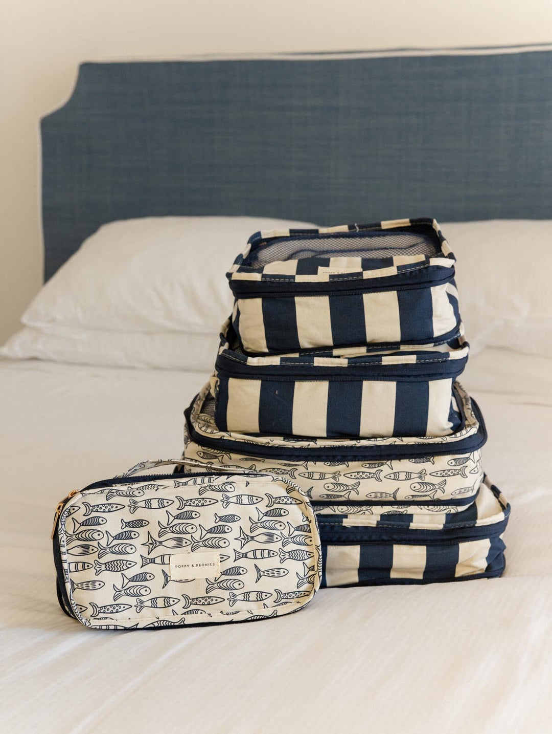 Set of navy and white patterned packing cubes on a bed