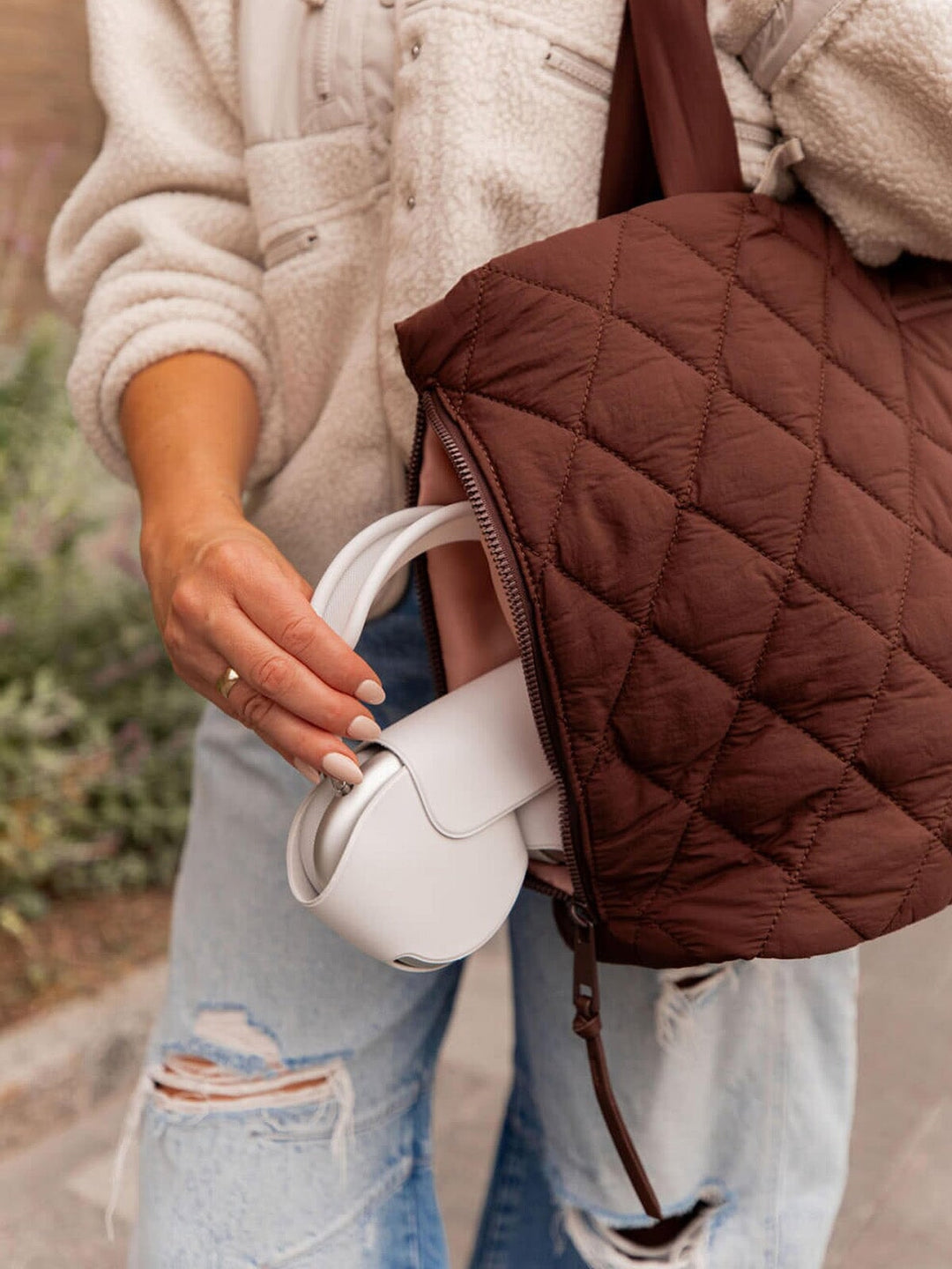Person putting headphones into a brown quilted bag 