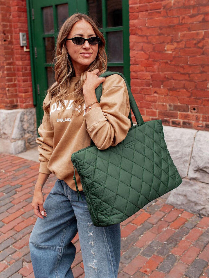 Woman holding a green quilted handbag in an urban setting