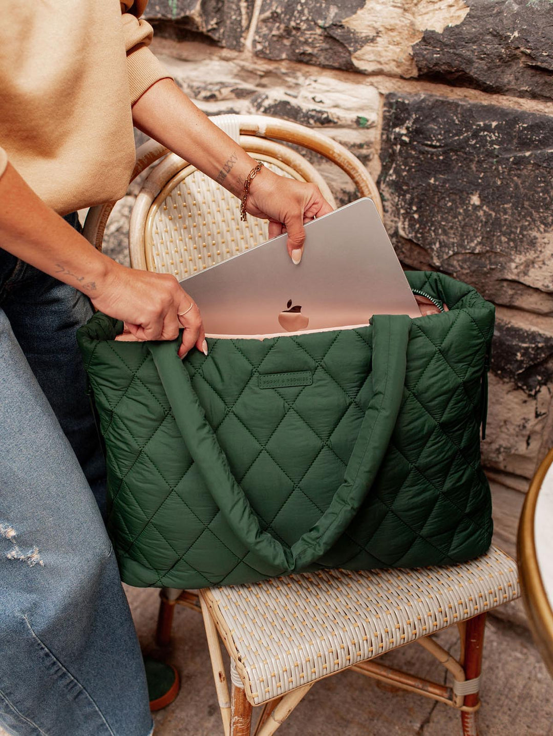 Person placing a laptop into a green quilted bag