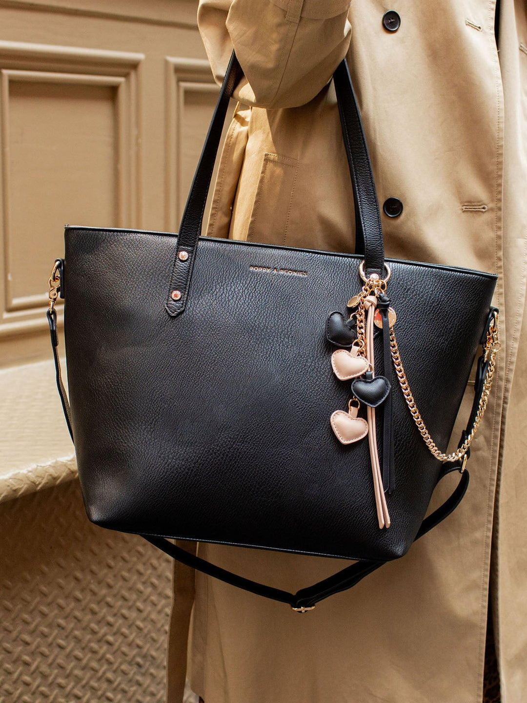 Black vegan leather tote bag with a pink and black heart bag charm.