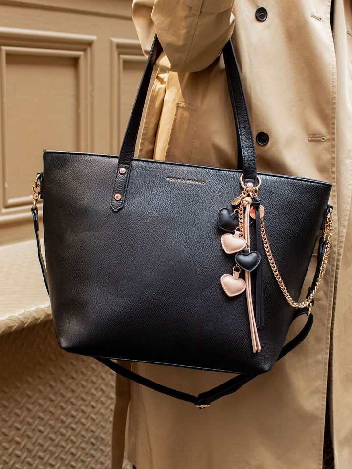 Black vegan leather tote bag with a pink and black heart bag charm.