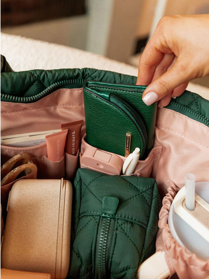Person organizing items in a green tote bag.
