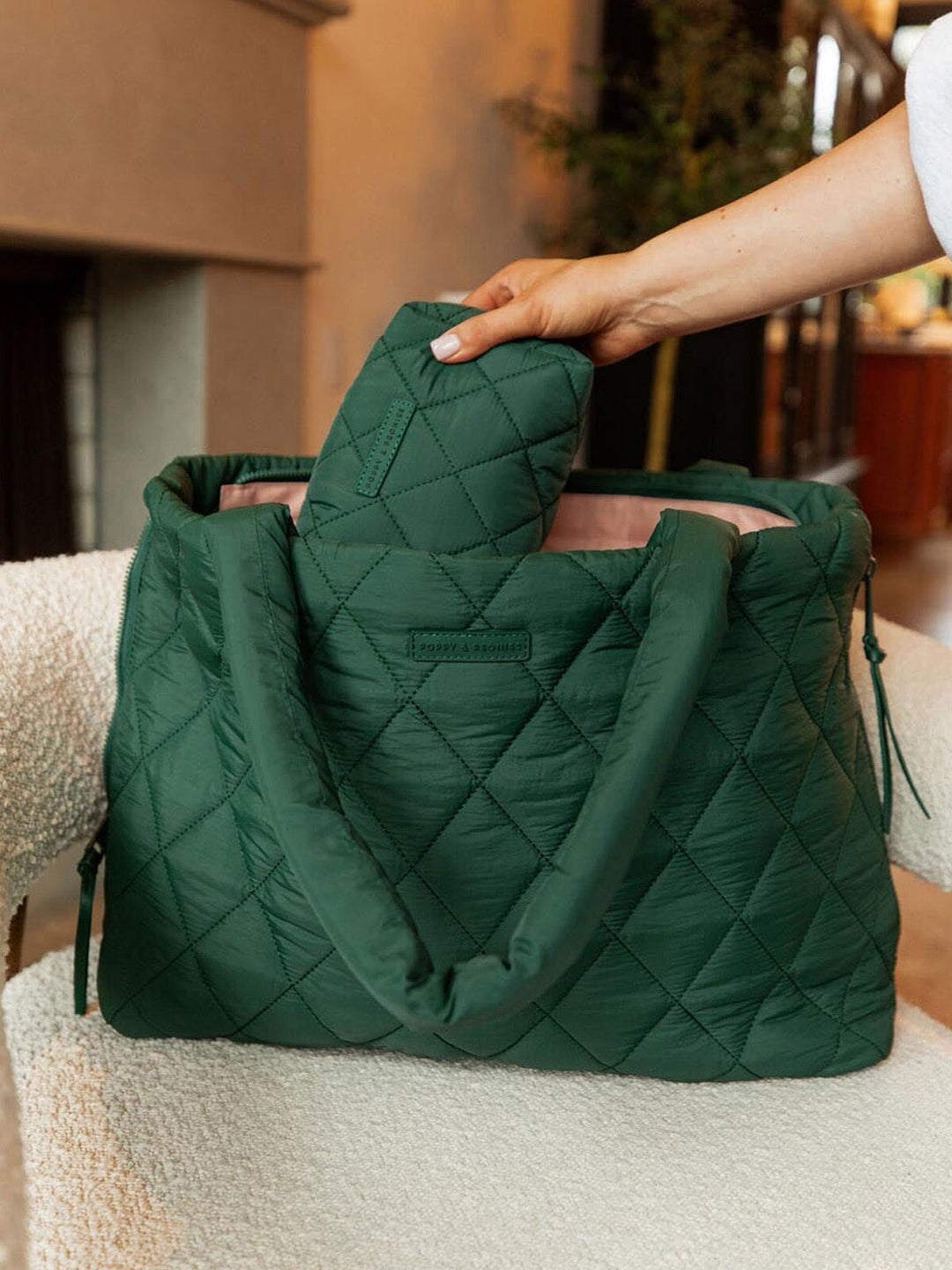 Woman putting a quilted cosmetic bag into a green quilted tote bag