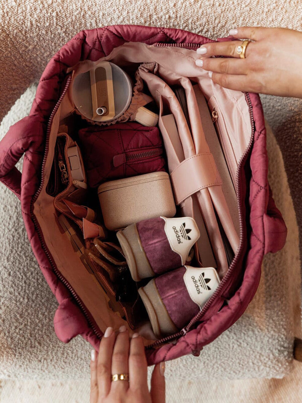 Open berry coloured quilted bag with various items