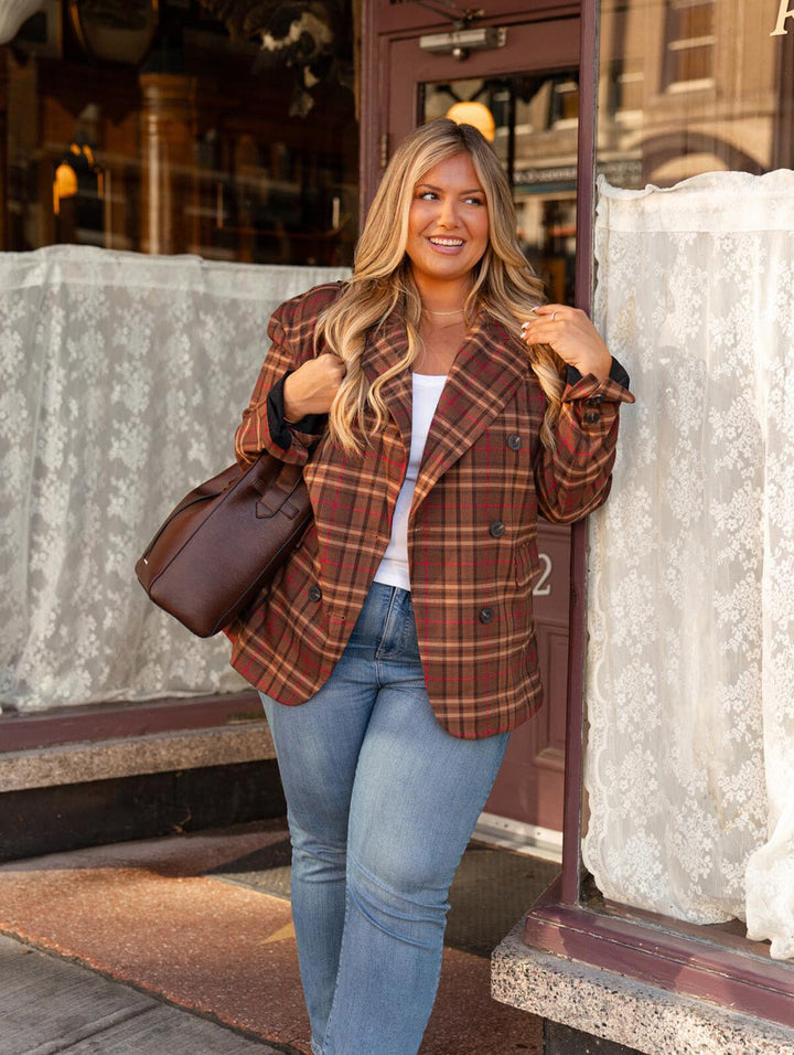Poppy & Peonies The Knot Shoulder Bag in Espresso styled over the shoulder by a woman in sunglasses and a brown plaid blazer, holding a coffee cup.