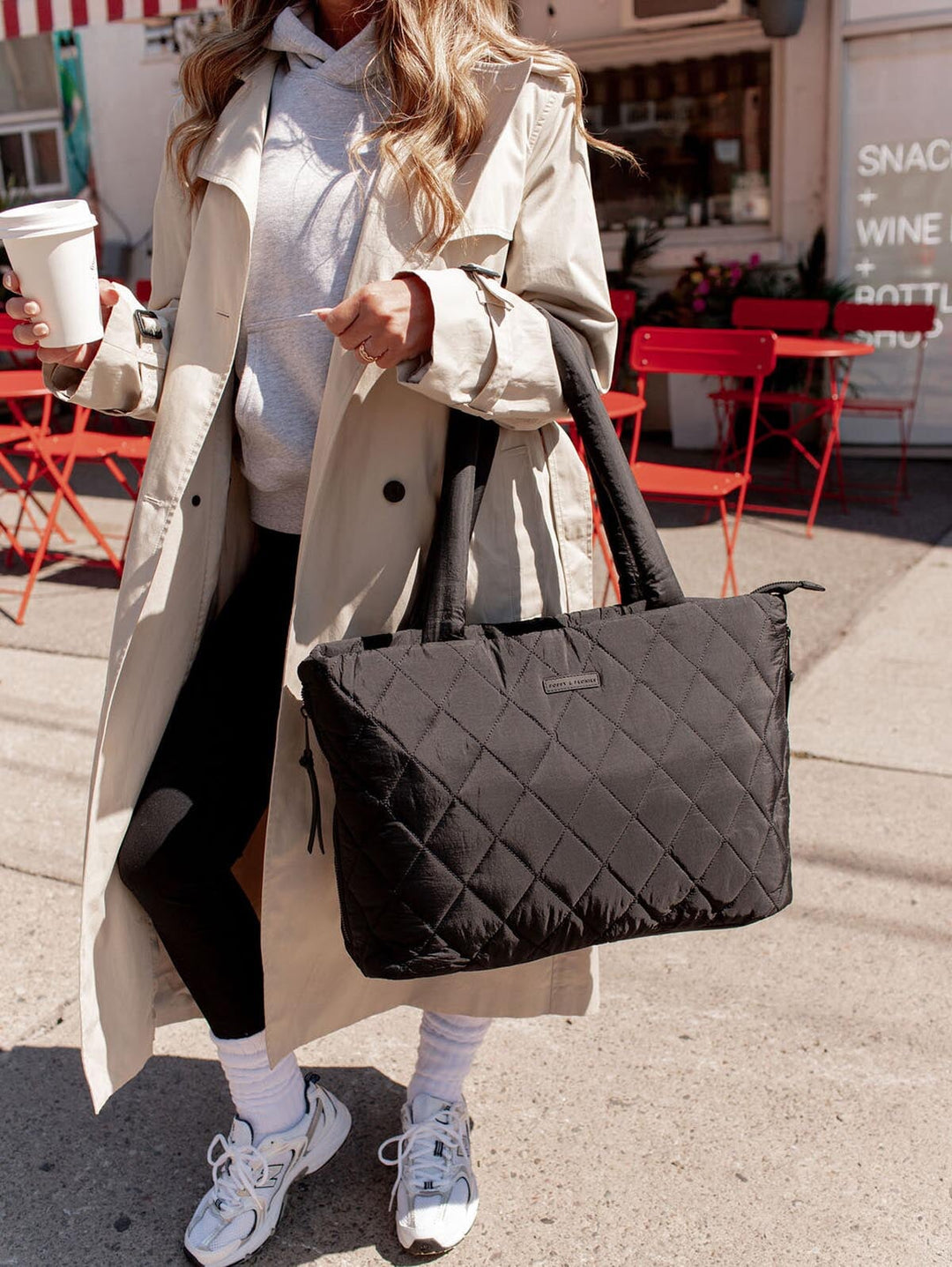 Person holding a black quilted bag on a city street