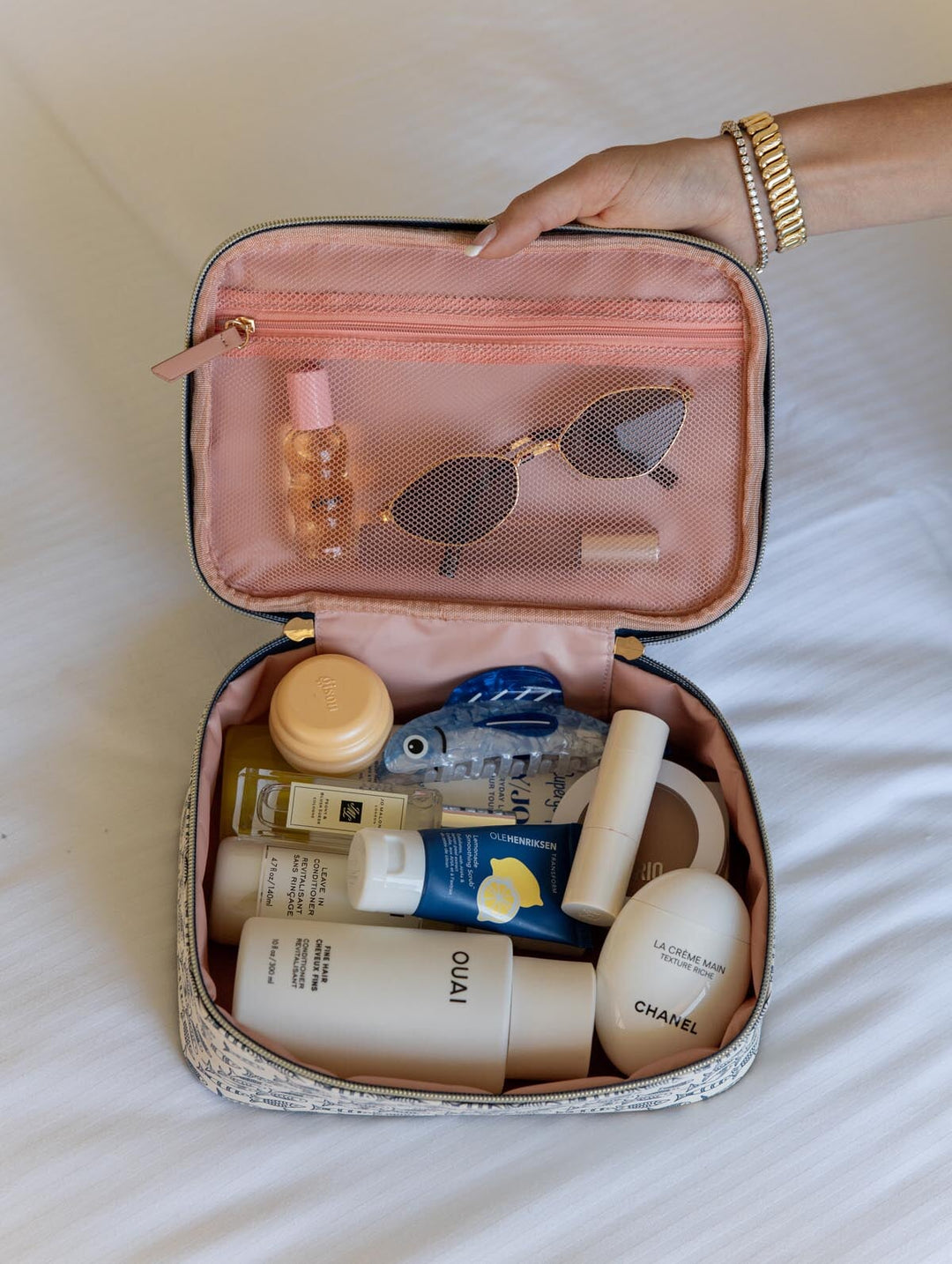 Cosmetic bag with skincare products and sunglasses on a light background