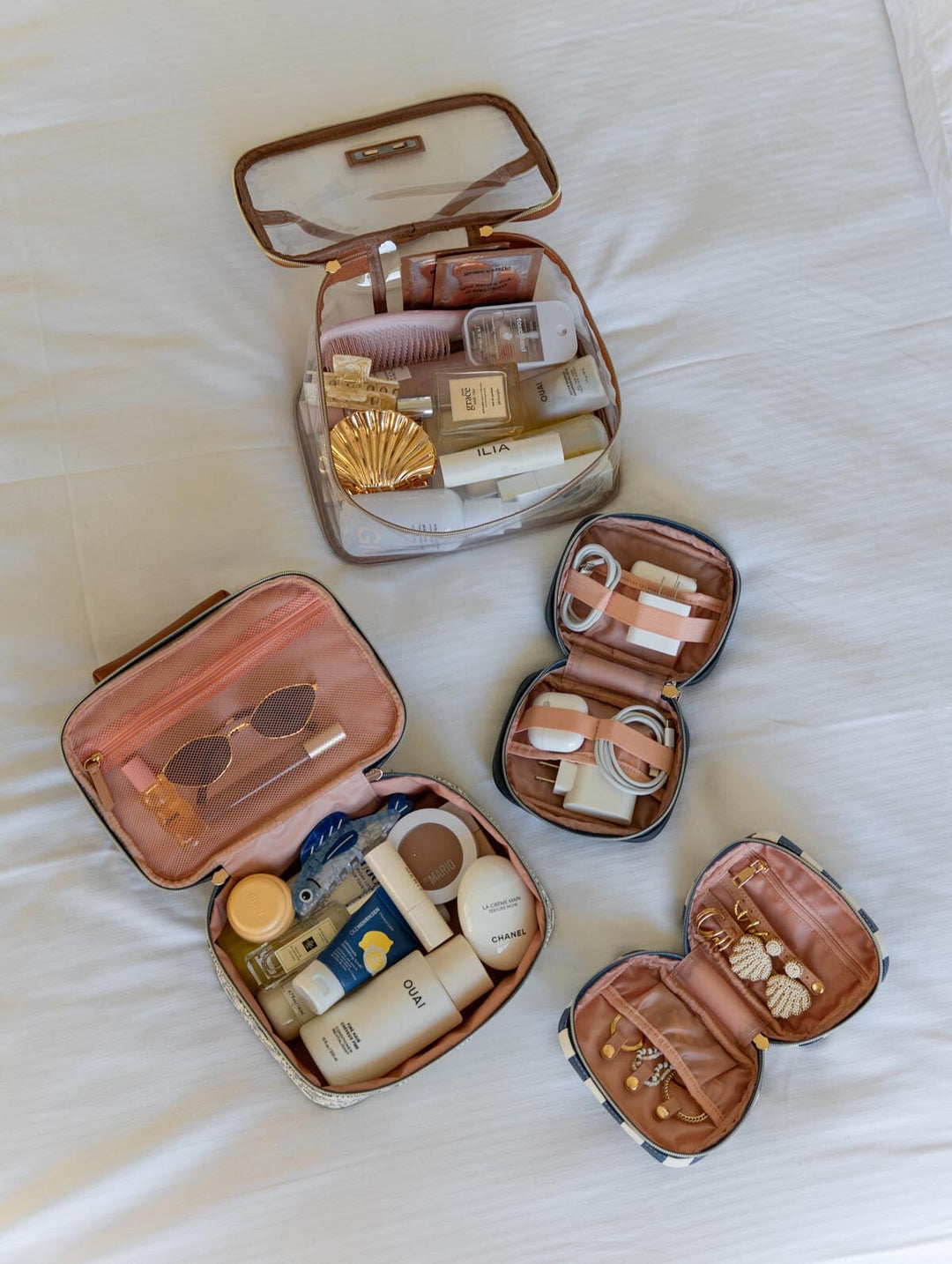 Set of small travel cases with toiletries and jewelry on a white surface