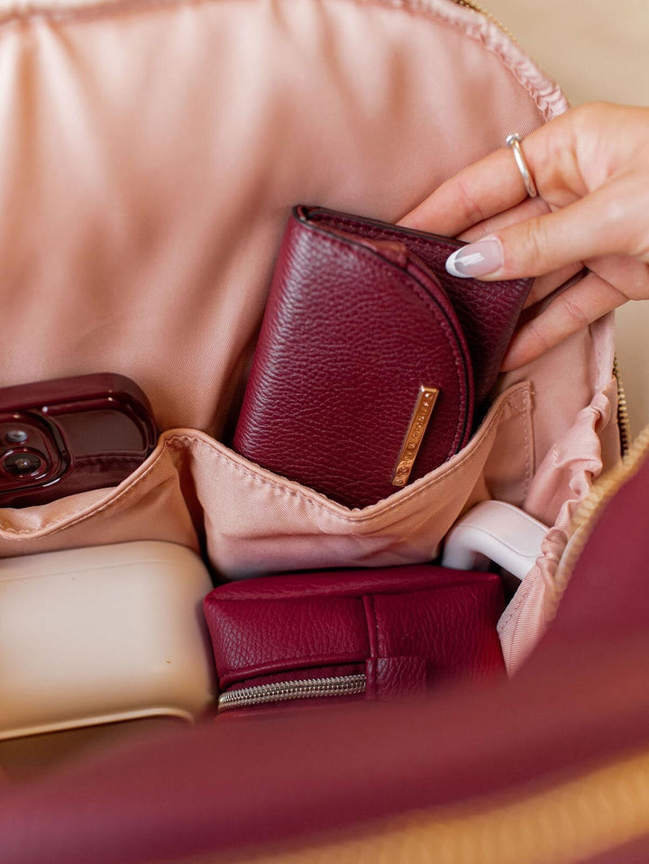 Person putting a vegan leather wallet into a backpack